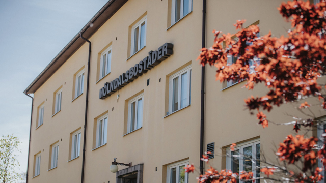 Gult våningshus med tre våningar med skylten Mölndlasbostäder på fasaden.