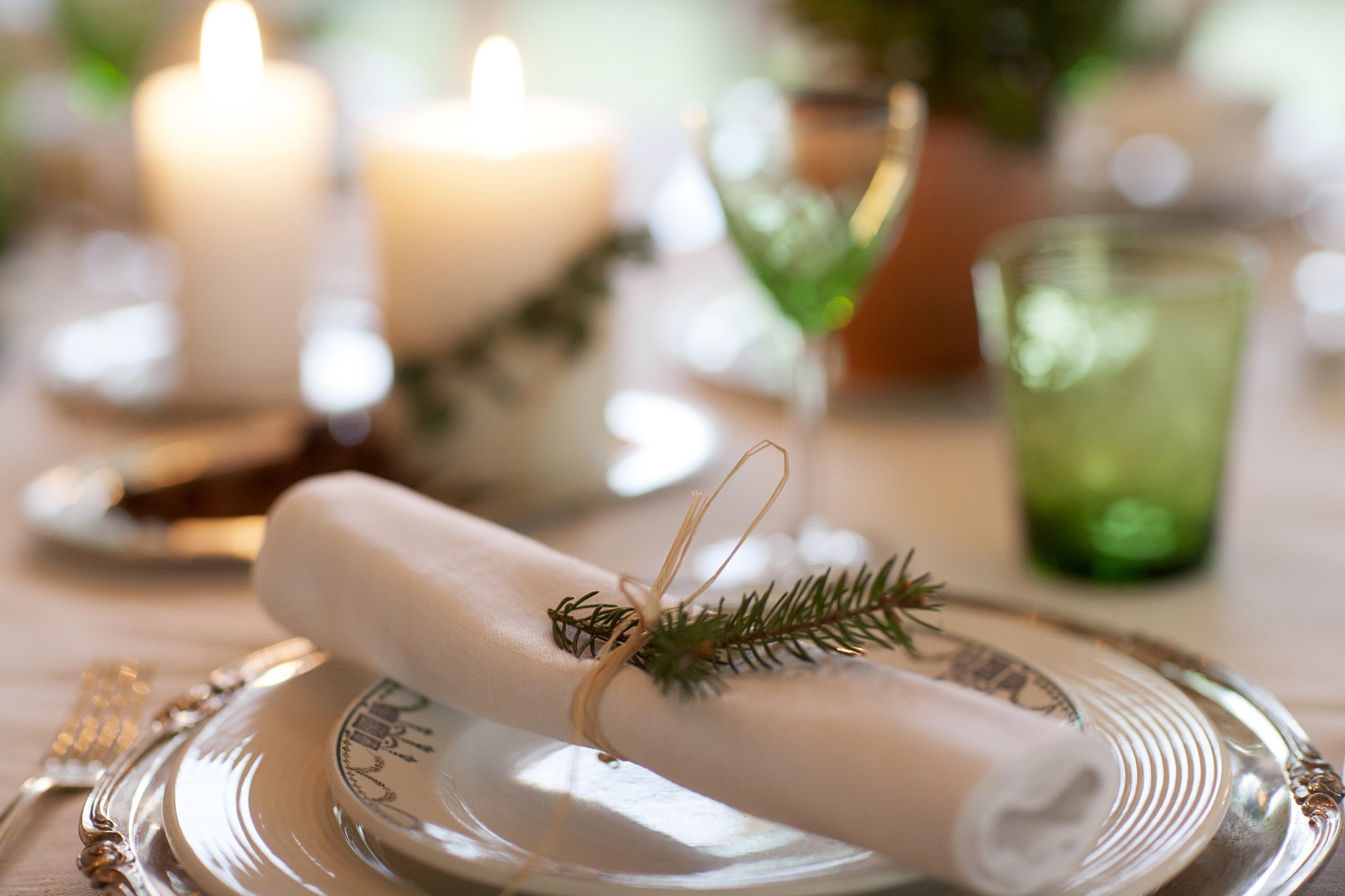 En julig dukning med vita servetter, snöre och grankvist.