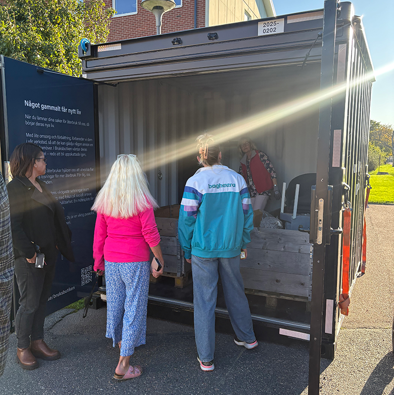 Fyra personer står vid en öppen återbrukscontainer