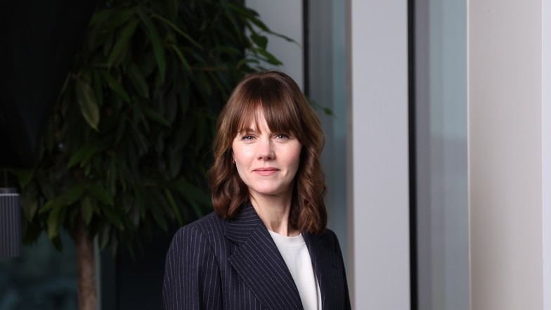 En porträttbild på en kvinna med mörkt hår klädd i kavaj. 