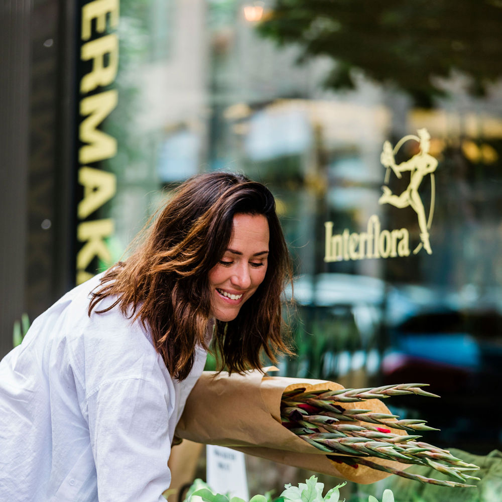 ung kvinna kikar på växter utanför Interflora en sommardag. 