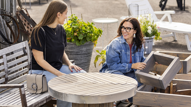 Två kvinnor samtalar vid ett träbord vid ett återbruk