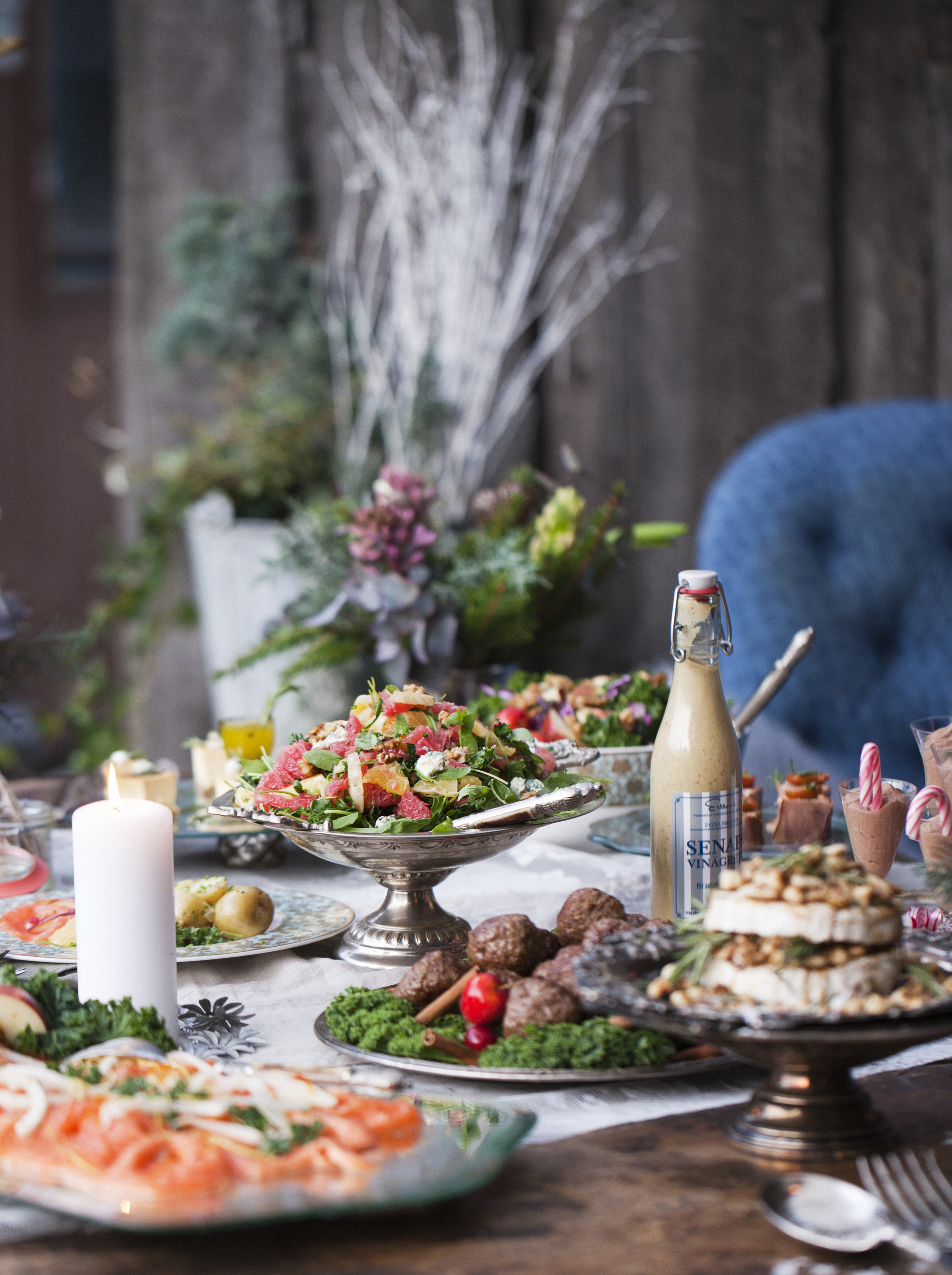 Ett vackert uppdukat julbord med sallad, köttbullar brieost i förgrunden. 
