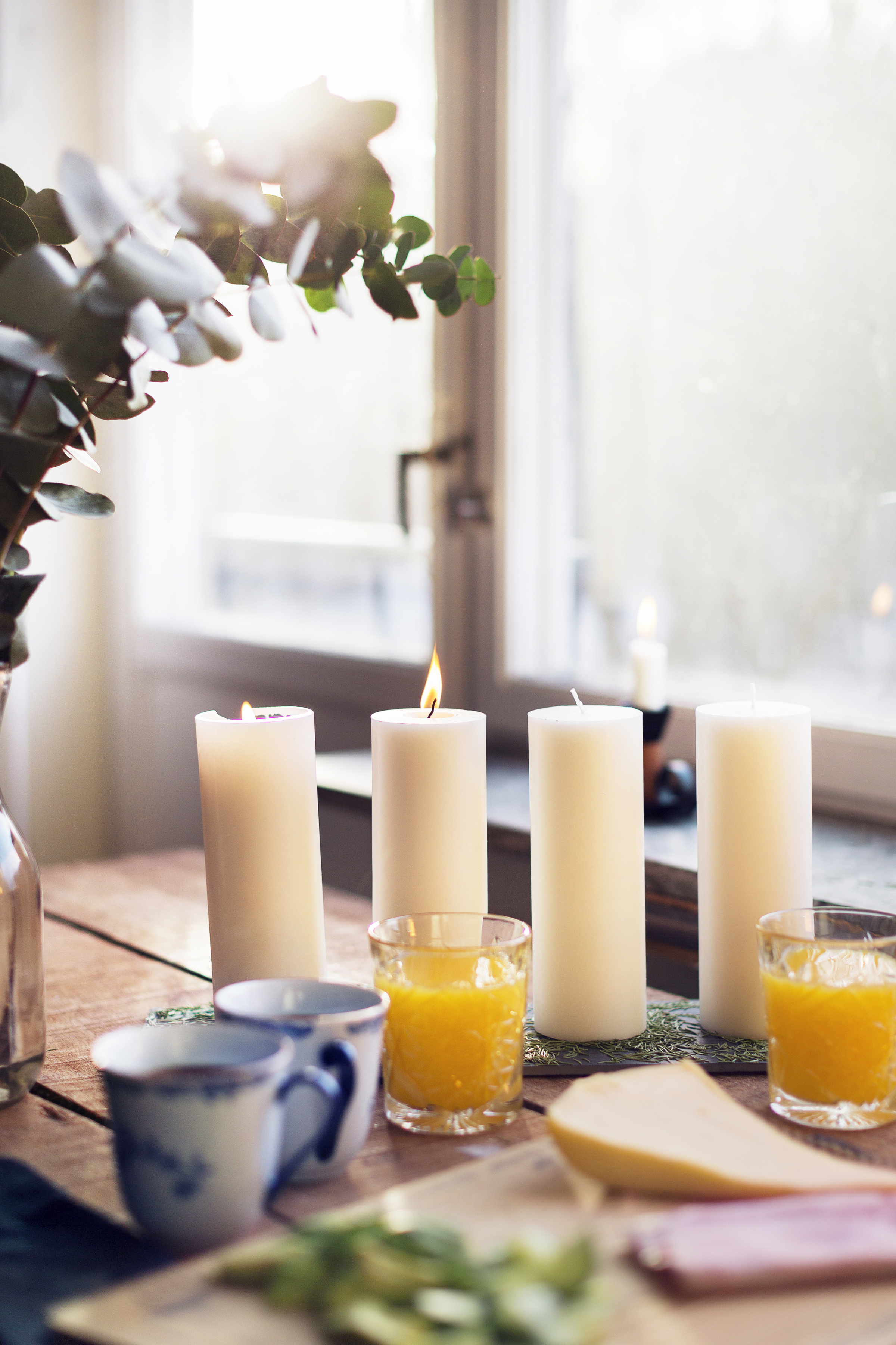 Fika i advent. Kaffe, juice, smörgåsar och fyra stora ljus på en lång bricka.