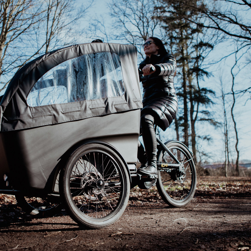 En kvinna kör en lastcykel i ett höstligt landskap. 