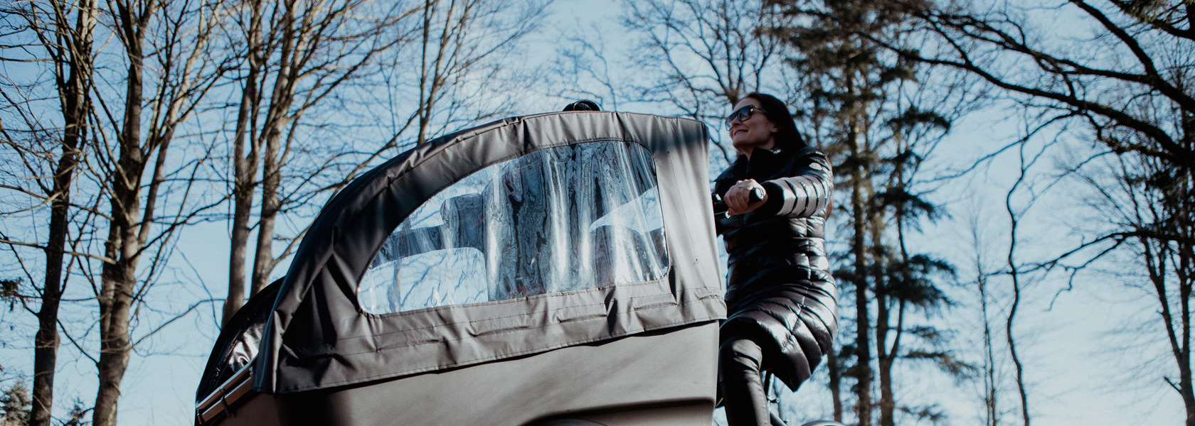 En kvinna kör en lastcykel i ett höstligt landskap. 