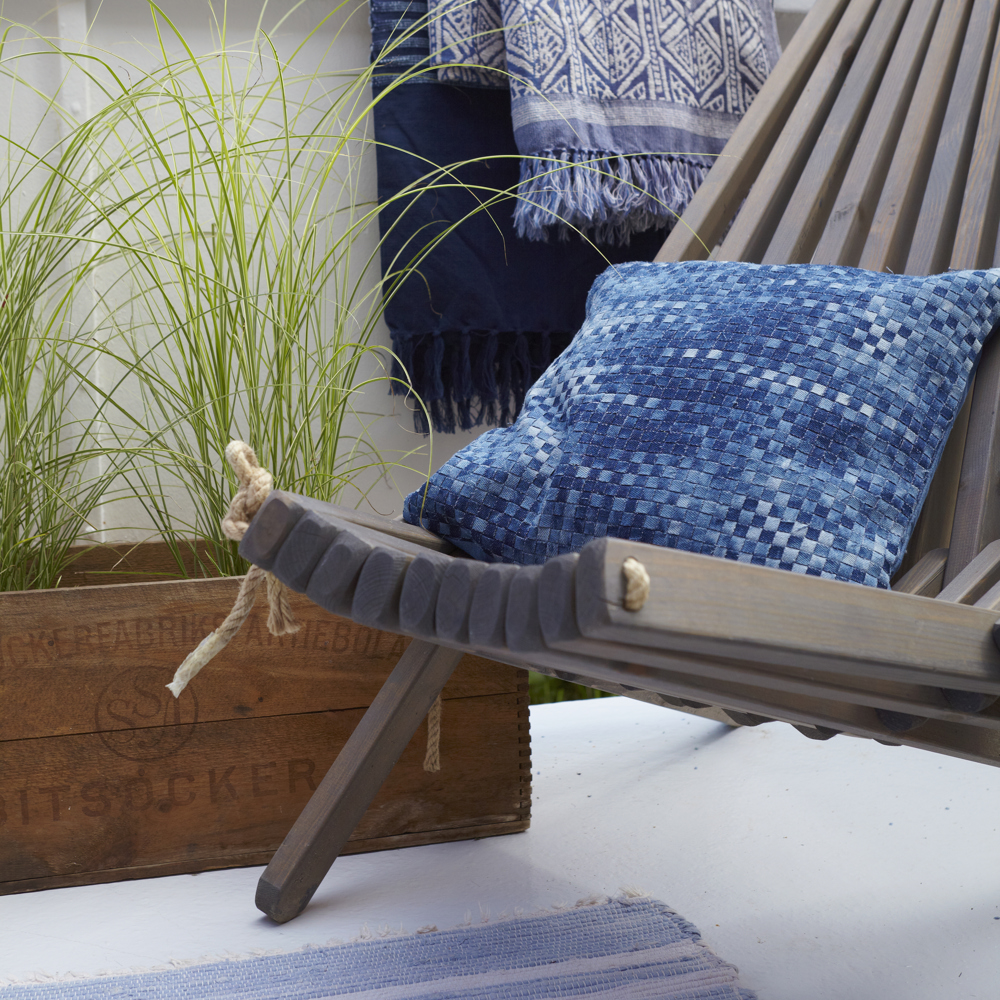 Närbild på en blomlåda som står på balkonggolvet med högt gräs i.